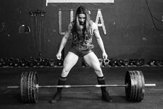 a woman with long hair and boots is holding a barbell in a black and white photo