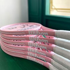 five pink tennis rackets sitting on top of a green table