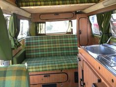 the interior of an old camper van with green plaid upholster and wood trim