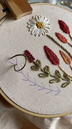 a close up of a embroidery on a piece of cloth with flowers in the middle