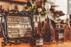 bottles of liquor are lined up on a bar counter with a sign in the background