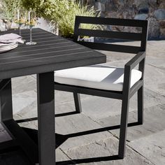 an outdoor table with two chairs and a wine glass on the table next to it