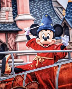 mickey mouse waving to the crowd in front of disney's castle at disneyland world