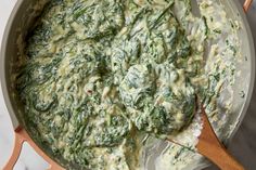 spinach and cheese sauce in a pot with a wooden spoon on a marble counter top