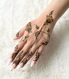 a woman's hand with hennap and flowers painted on the top of it