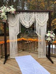 an outdoor wedding ceremony setup with white and pink flowers on the ground, hanging from a wooden structure