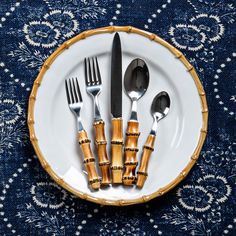 a plate with silverware and bamboo utensils in it on a blue table cloth