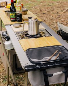 an outdoor table with a stove and cooler on it in the middle of a field