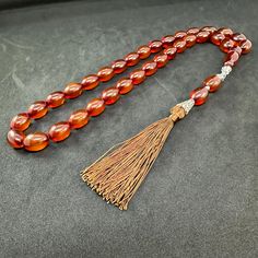 ⭐️ Tasbih is completely handmade & masterwork. ⭐️ Special oval cut, large size and honey color bakelite beads. ⭐️ It has perfectly handcrafted rope tassel.  ⭐️ 100% Brand New Condition. ℹ️ About Material; Faturan & Bakelite (Catalin) is artificial resin in its simplest definition. It is an artificial imitation of real amber, that is, petrified pine tree resin. Catalin was produced to replace natural amber due to its very expensive and fragile nature. The most important feature is that it is extr Traditional Orange Beaded Gems And Cabochons, Traditional Amber Rosary With 8mm Beads, Traditional Adjustable Rosary With Polished Beads, Traditional Amber Rosary, Traditional Adjustable Amber Beads, Traditional Amber Rosary With Round Beads, Traditional Brown Beaded Rosary, Traditional Beaded Brown Rosary, Traditional Faceted Oval Beads