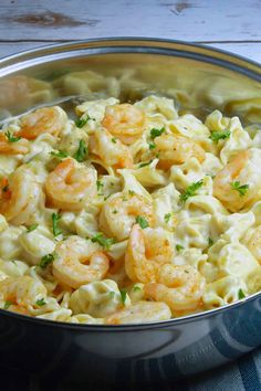 a silver bowl filled with pasta and shrimp