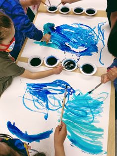 children are painting with blue paint on paper