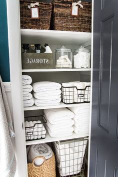 an organized closet with baskets and towels