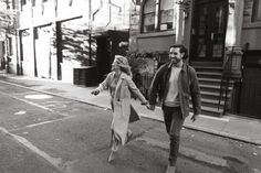 a man and woman walking down the street holding hands