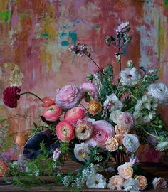 a vase filled with lots of flowers on top of a wooden table next to a wall