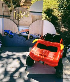 a red toy truck sitting on top of a wooden floor next to a sign that says monster trucks