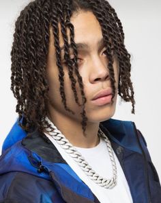 a young man with dreadlocks on his head wearing a blue jacket and white t - shirt