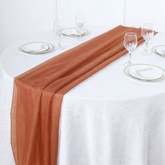 the table is set with white and orange plates, silverware, and an orange ribbon