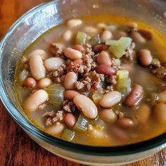 a bowl filled with meat and beans on top of a wooden table