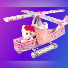 a hello kitty doll in a pink purse on top of a toy helicopter with handlebars