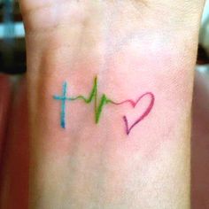 a small wrist tattoo with a heart and cross on it