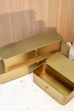 three gold colored boxes sitting on top of a white countertop next to each other