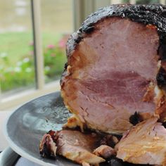 a large piece of meat sitting on top of a black plate next to a window