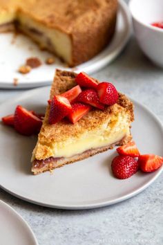 a slice of cheesecake with strawberries is on a plate next to the rest of the cake