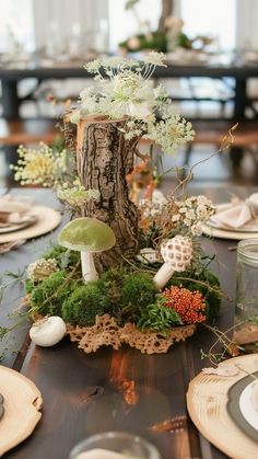 a table topped with plates and vases filled with flowers next to a tree stump