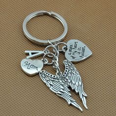 an angel keychain with two hearts and the word mom written on it's side