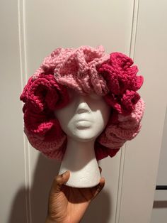 a white mannequin head wearing a pink crocheted hat with flowers on it