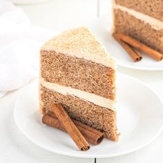 two slices of cake on white plates with cinnamon sticks