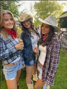 three women in cowboy hats are posing for the camera with one woman holding a drink