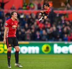 a soccer player is jumping in the air to catch a ball with his mouth wide open