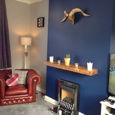 a living room with blue walls and a red leather chair in front of a fire place