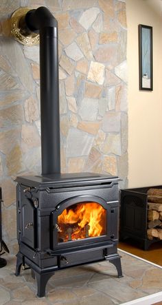 a wood burning stove in a room with stone walls and flooring on either side