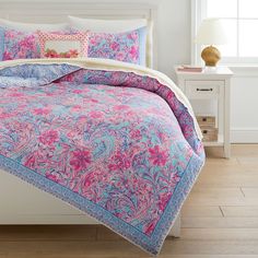 a bed with pink and blue comforters on top of it