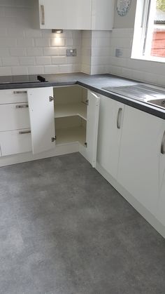 an empty kitchen with white cupboards and black counter tops