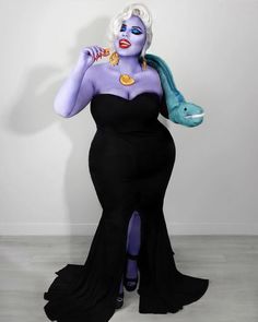 a woman in a black dress with purple hair and blue makeup is holding a fish