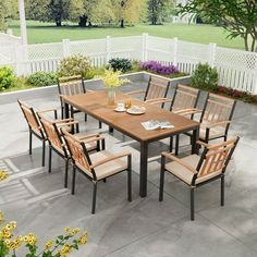 an outdoor dining table and chairs on a patio with flowers in vases next to it