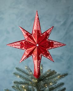 an ornament shaped like a star on top of a christmas tree