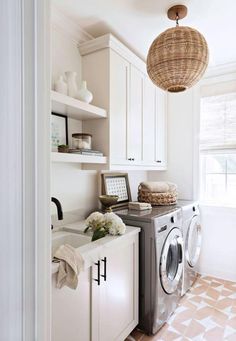 a washer and dryer in a white laundry room with open shelving on the wall