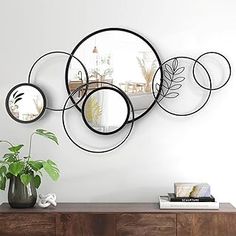 three circular mirrors mounted on the wall above a wooden table with a potted plant