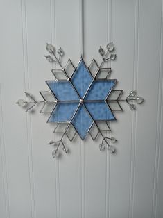 a blue snowflake hanging on the side of a white wall next to a door