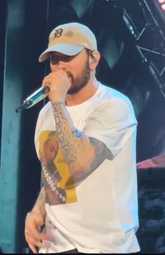 a man with tattoos on his arm holding a microphone to his mouth while standing in front of a stage