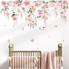 a baby's room with pink flowers on the wall and a gold crib