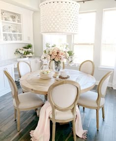 a dining room table with white chairs and a chandelier hanging from the ceiling