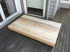 a wooden platform sitting on top of a porch next to a door with windows in the background