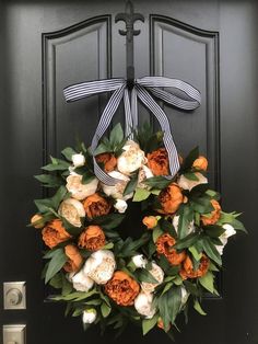 an orange and white wreath on a black door