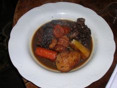 a white bowl filled with meat and vegetables