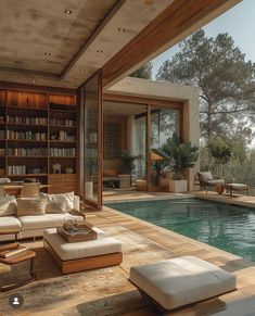 a living room with a couch, chair and book shelf next to a swimming pool